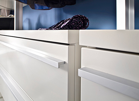 Schubladenschrank Premium von frank Schranksysteme Bild von einem weißen seidenmatt glänzendem Schubladenschrank mit zwei Schubladen, jede Schublade mit einer silbernen schmalen langen Griffleiste.