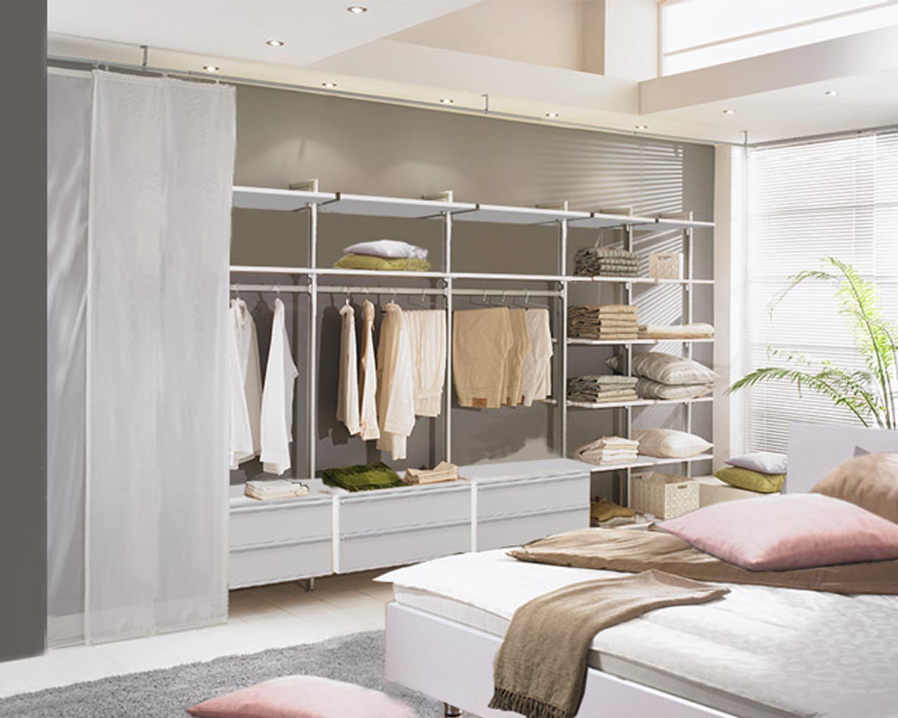 Helles Schlafzimmer mit einem komfortablen Bett und einem geräumigen offenen Kleiderschrank mit Schiebevorhängen vor dem Schrank, Profile Silber, Holzböden und Schränke Weiß.