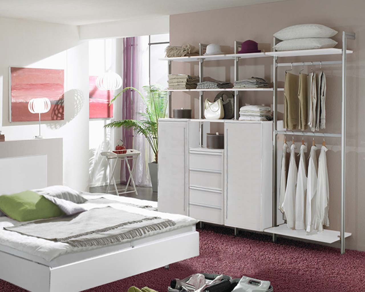 Ein Schlafzimmer mit einem Bett, einem offenen Kleiderschrank in Weiß mit 2 großen Schrankelementen mit Türen und 4 Schubladen, vielen Regalen und Kleiderstangen, gemütlich und einladend eingerichtet.