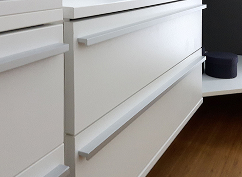 Schubladenschrank Soft von frank Schranksysteme Bild von einem weißen Schubladenschrank mit zwei Schubladen, jede Schublade mit einer silbernen schmalen langen Griffleiste vor braunen Fußboden.